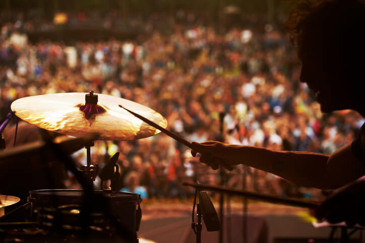 Cropped shot of a drummer playing in front of a large crowd at an outdoor music festival